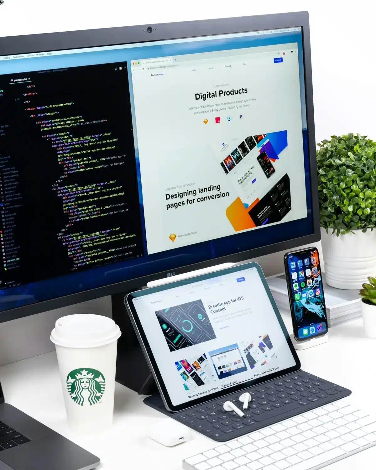 Desk with a monitor, tablet, iPhone, and a Starbucks coffee on it.