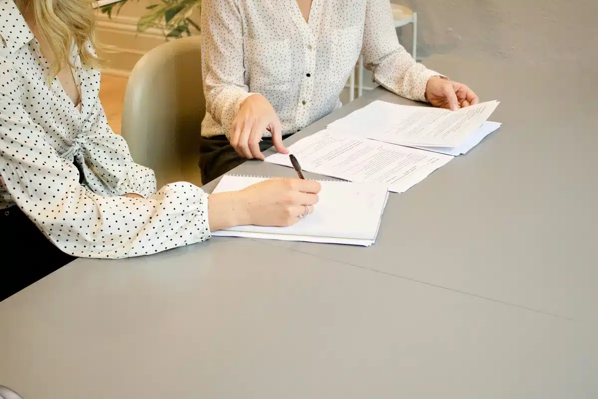 Two coworkers discussing and writing a rebranding RFP on a white paper