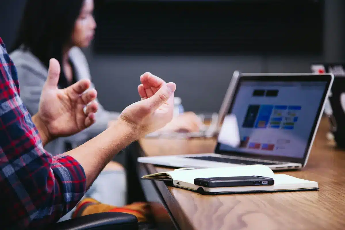 Person with red and blue flannel talking mid office meeting.