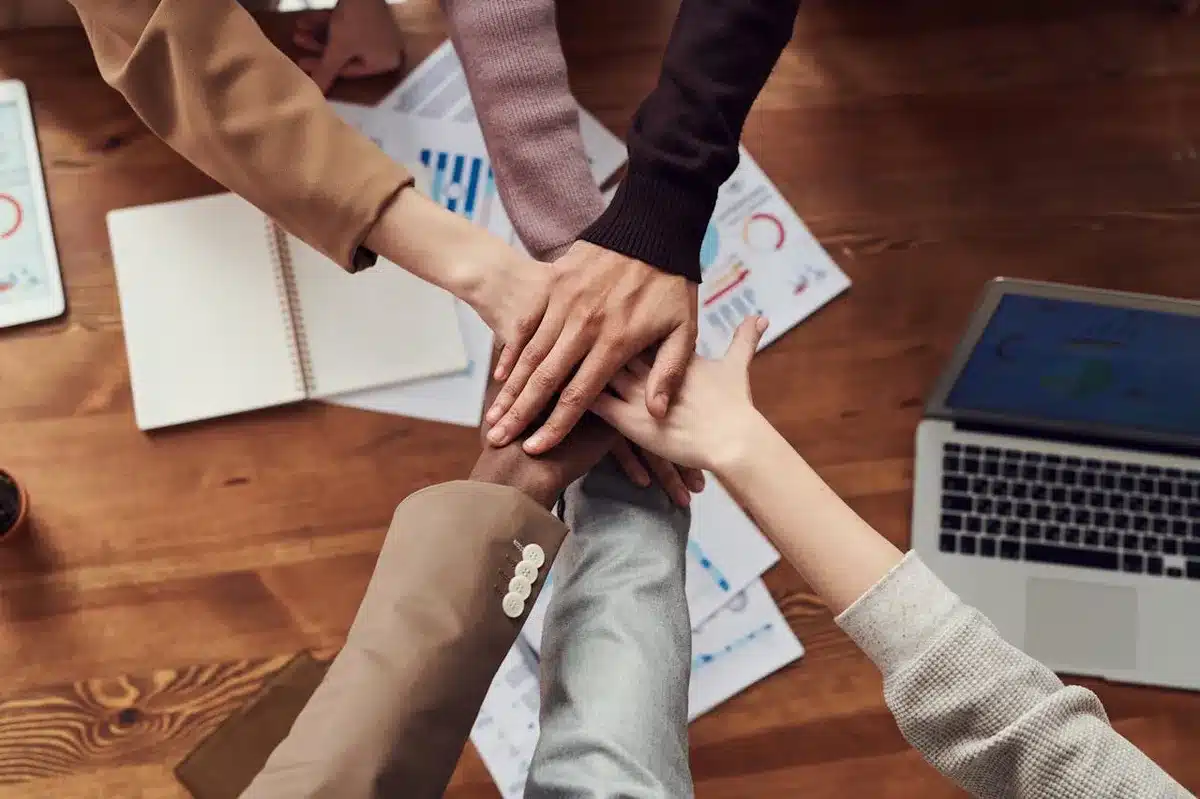Coworkers joining hands in cooperation on top of a wooden desk