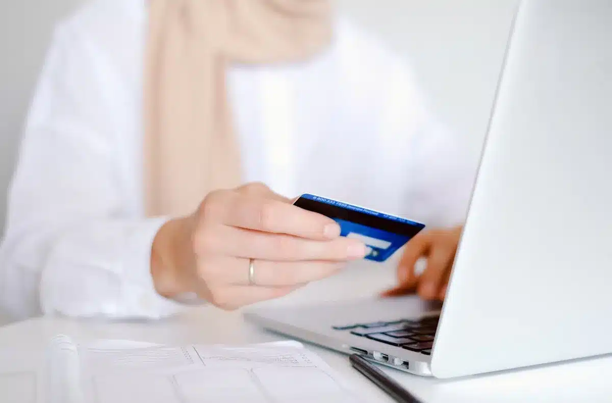 A person with a white shirt using their credit card online to buy a product they want
